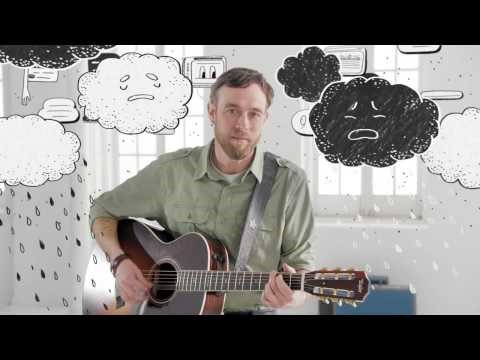 video screenshot white man playing guitar surrounded by cardboard rainy clouds with crying face