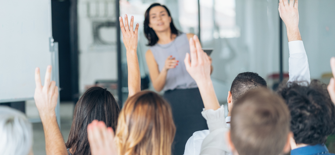 Group of employees in lead generation workshop raising arms to participate