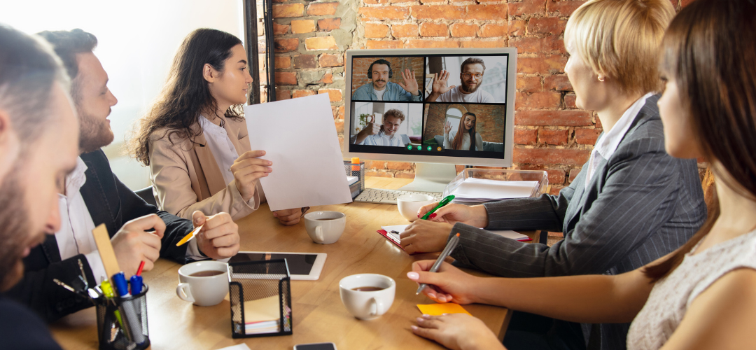 Marketing employees in a meeting having video conference with sales employees other employees